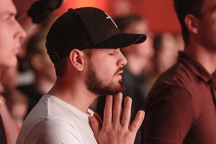Młody człowiek w czapce modli się