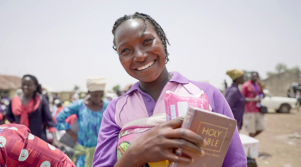 Kobieta trzyma w ręku nową Biblię i uśmiecha się.