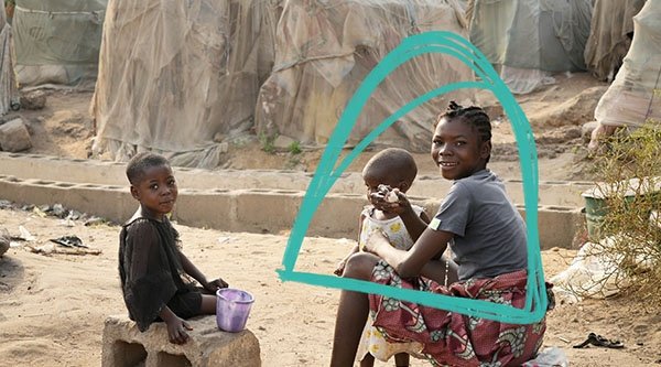  Dzieci siedzą na prowizorycznych krzesłach w afrykańskim obozie dla uchodźców.