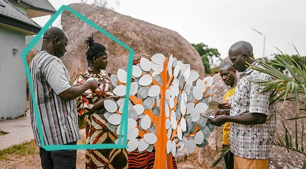Afrykańscy chrześcijanie stoją przed drzewem otuchy i czytają słowa otuchy.